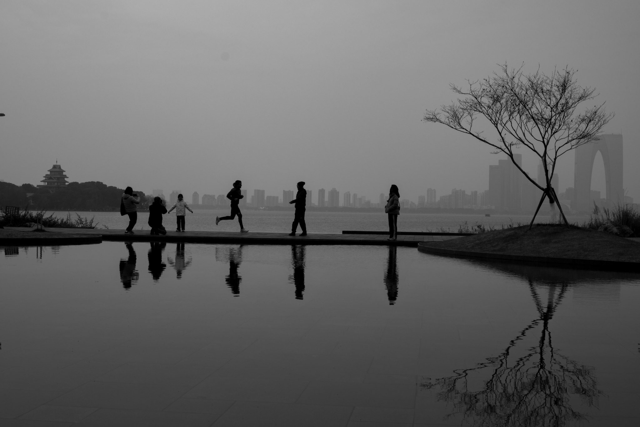 People walking beside a lake in China, reflected in the water